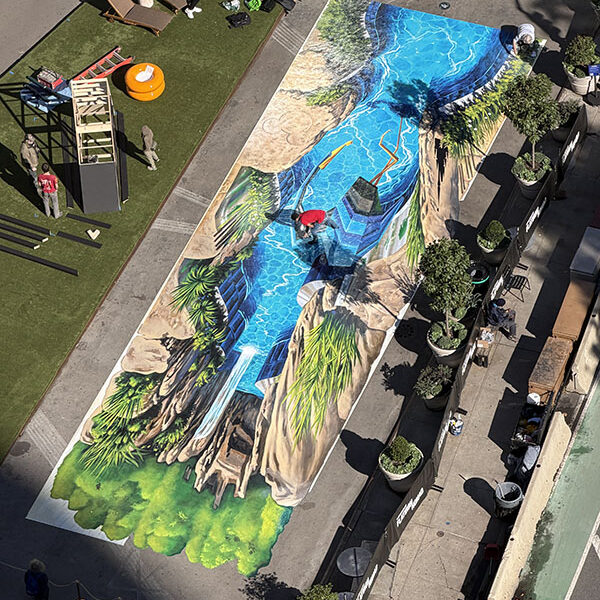 Disney Lakeshore Lodge 3D – Drone View Drone view of Tracy Lee Stum's 3D street art installation for Disney Lakeshore Lodge at Flatiron Plaza, revealing the elongated perspective design.