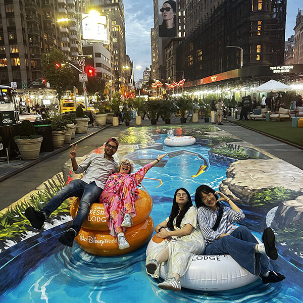 Anamorphic Street Art – Perspective View Visitors posing on inflatable tubes within Disney's Lakeshore Lodge interactive 3D lazy river street painting in New York City.