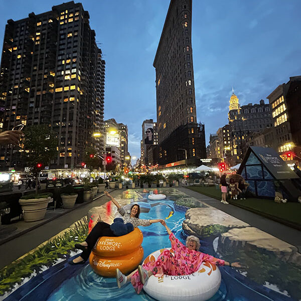 Anamorphic Street Art – Model Interaction Evening photograph of Disney Lakeshore Lodge 3D street art NYC installation, featuring an interactive lazy river illusion near the Flatiron Building.
